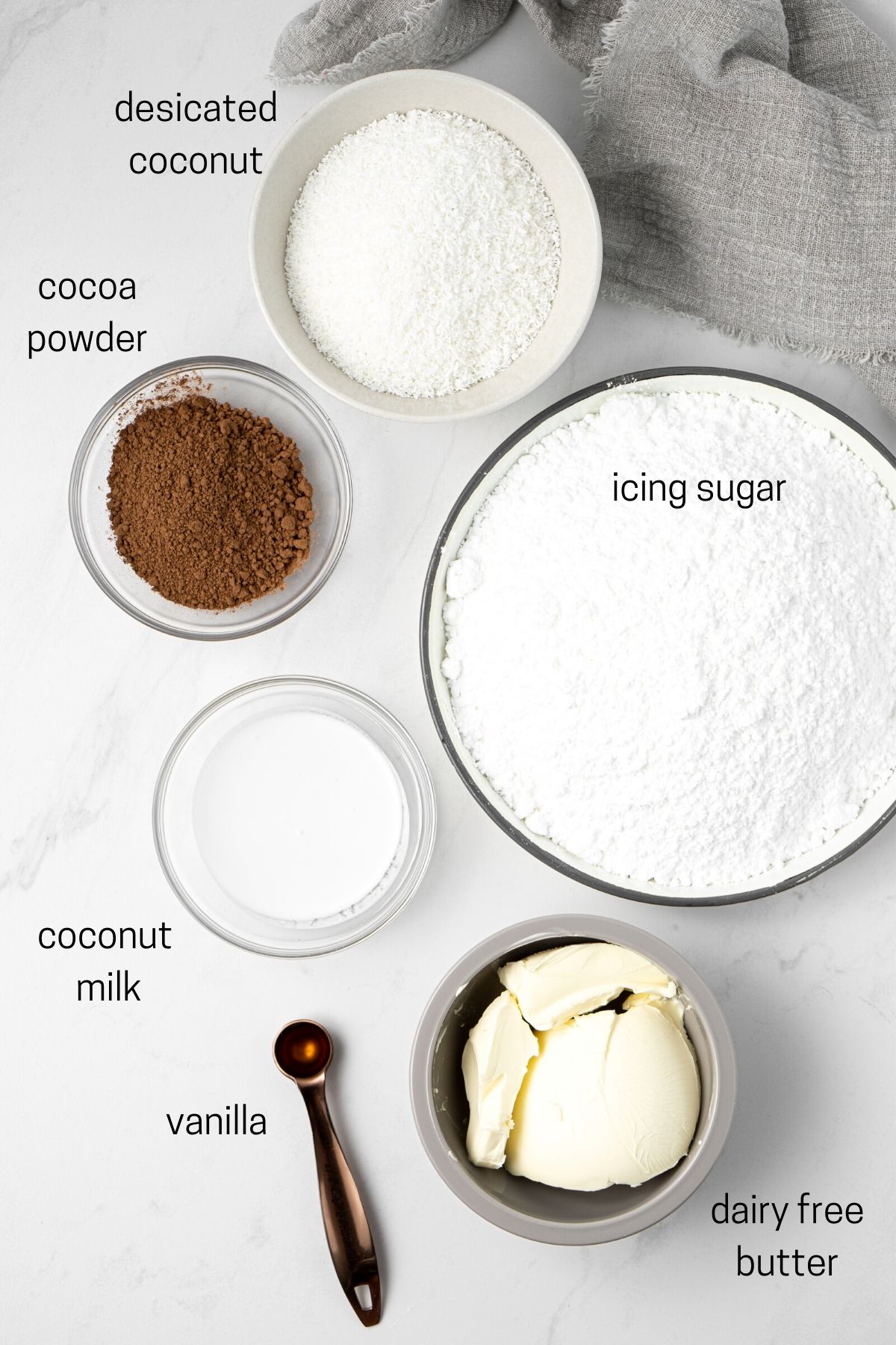 Ingredients for buttercream and chocolate icing laid out in small bowls.