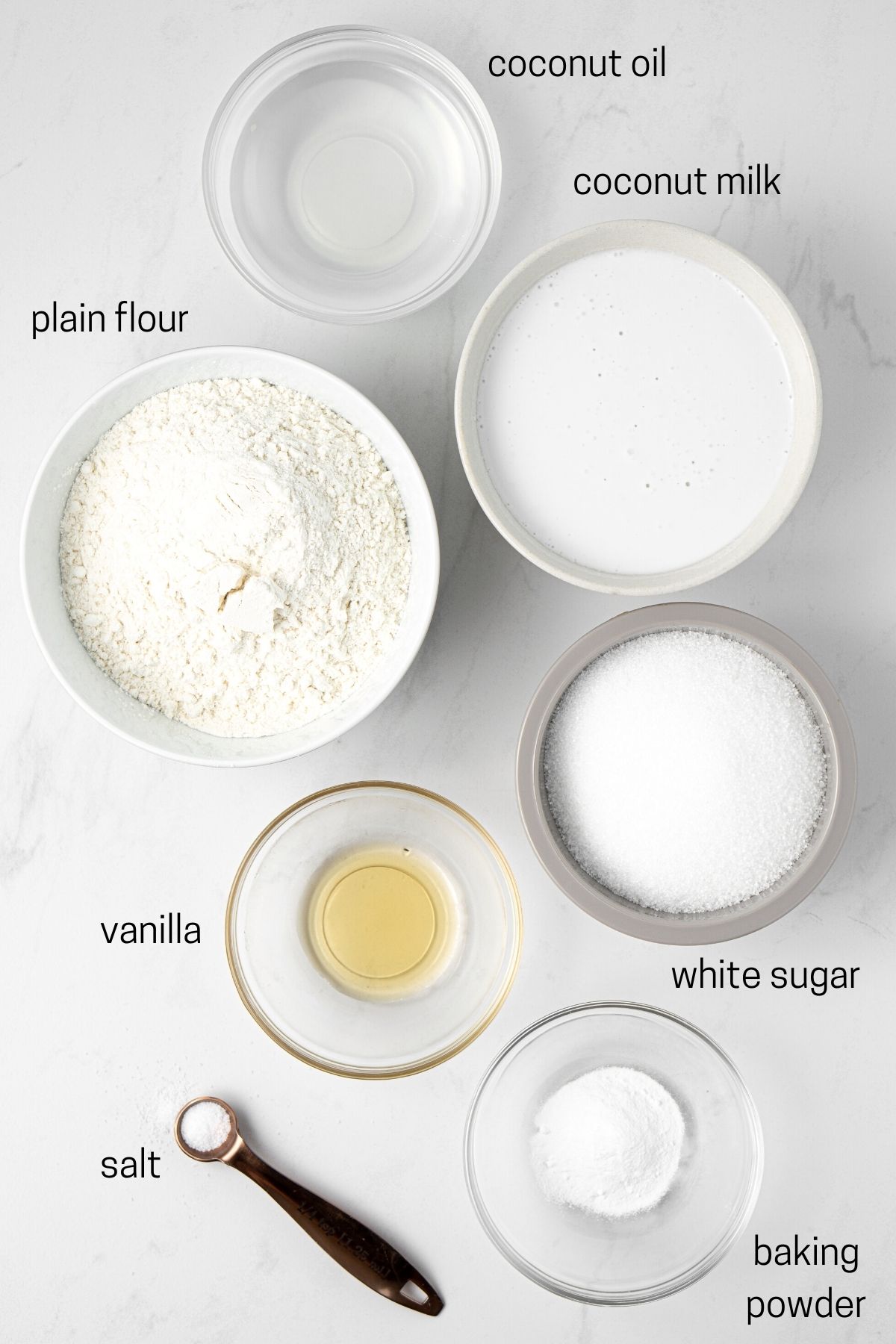 Ingredients for lamington cupcakes laid out in small bowls.