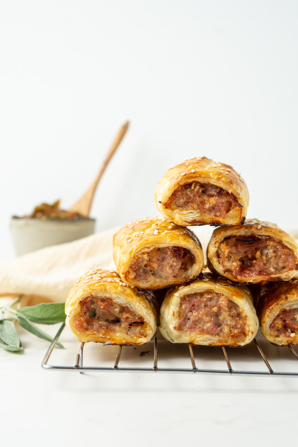 Cooked pork sausage rolls stacked on top of each other on a wire cooling rack.