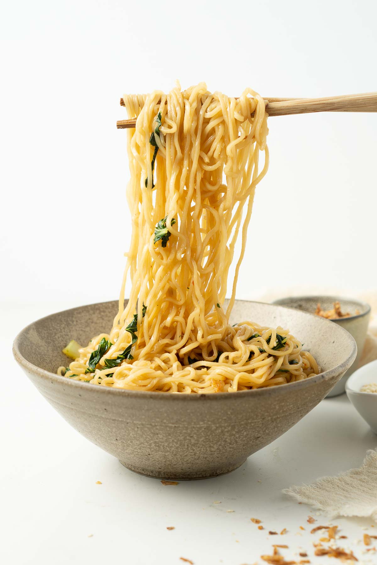 Bowl of noodles with large noodle pull with chopsticks. 