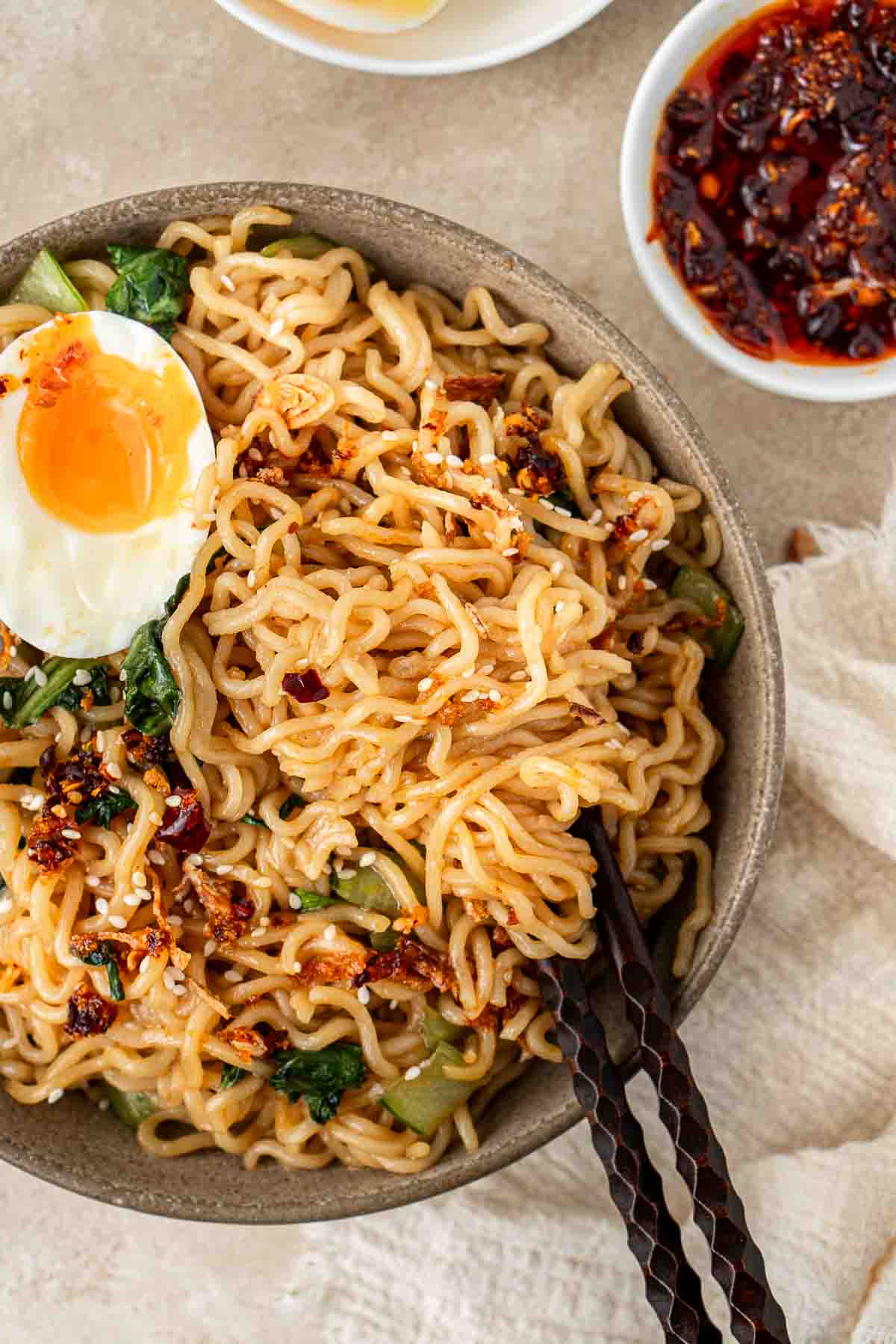 A bowl of 5 minute sweet and spicy noodles with an egg and chopsticks.
