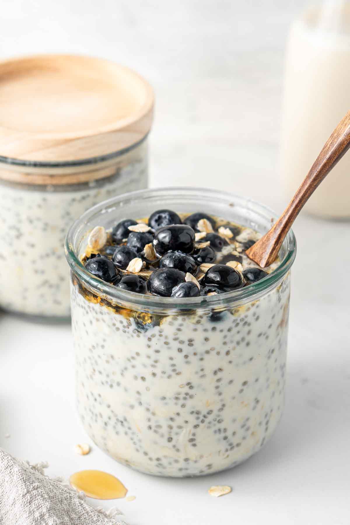 Overnight oats in a jar topped with fresh blueberries and a spoon.