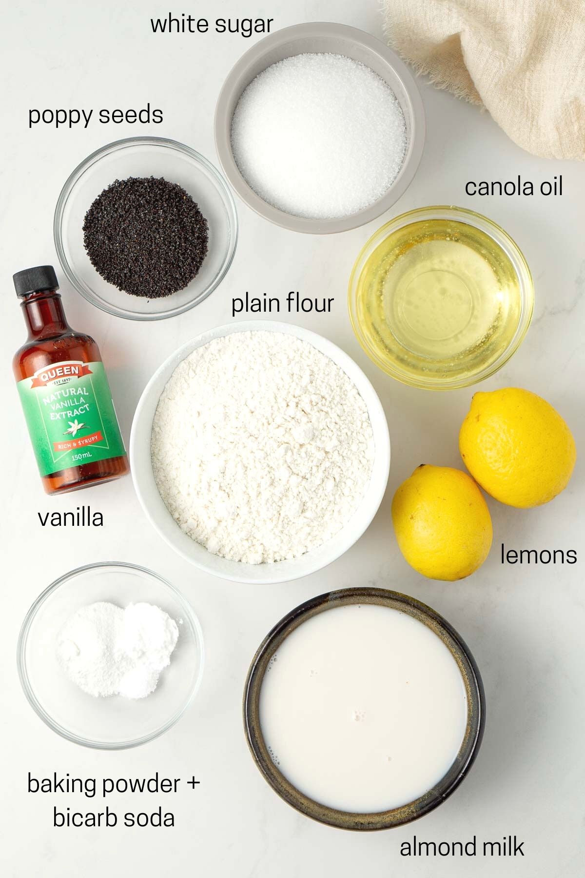 All ingredients needed for lemon poppy seed cake laid out in small bowls.