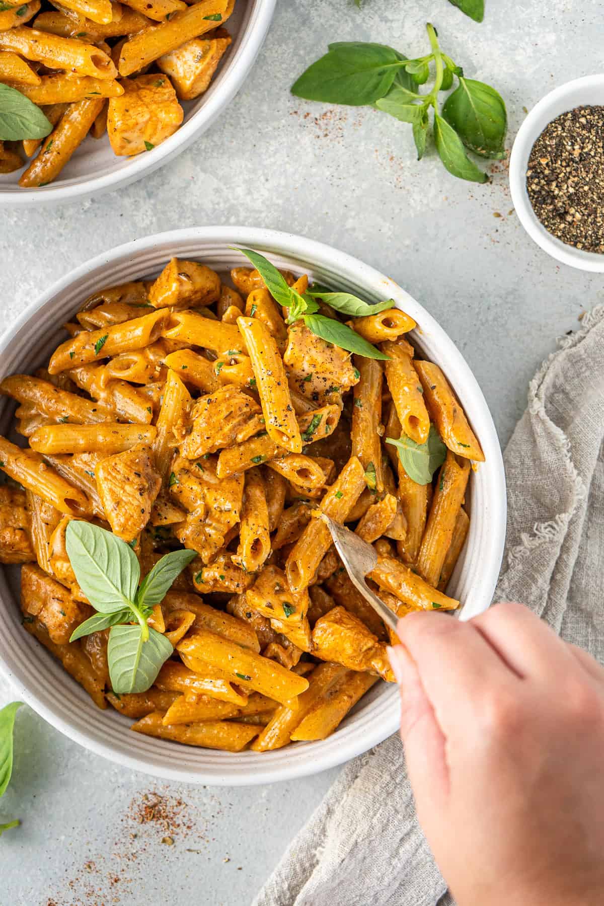 A hand using a fork to take a bite of the creamy cajun chicken pasta.