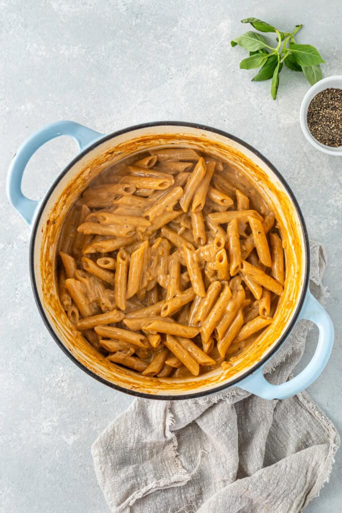 The pasta finished cooking in the sauce in the pot.