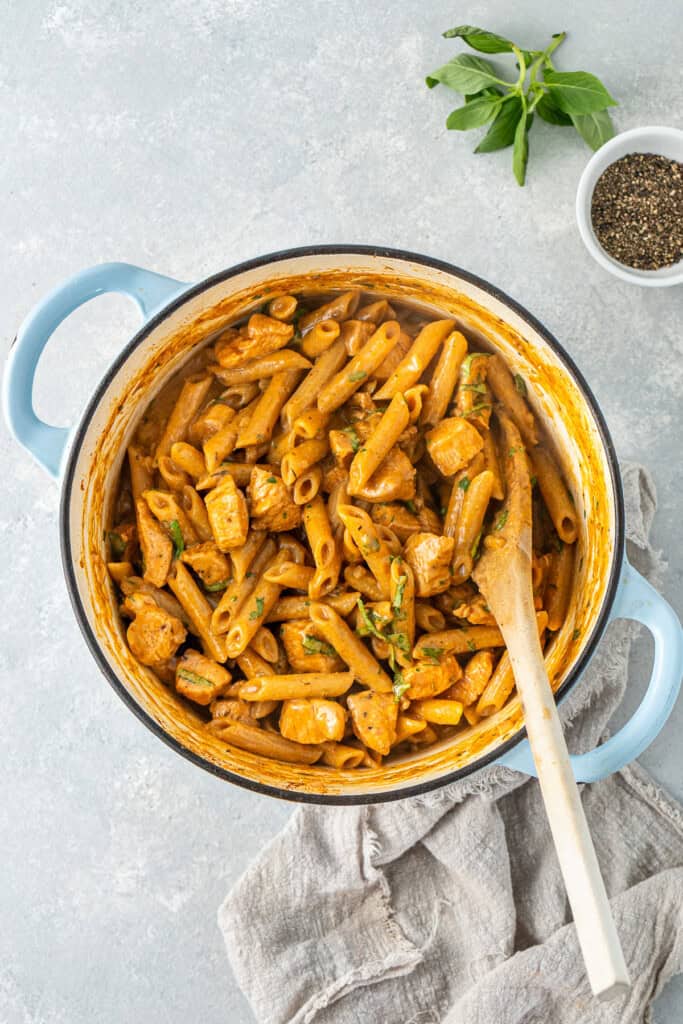 The Cajun chicken past in a pot with a wooden spoon.