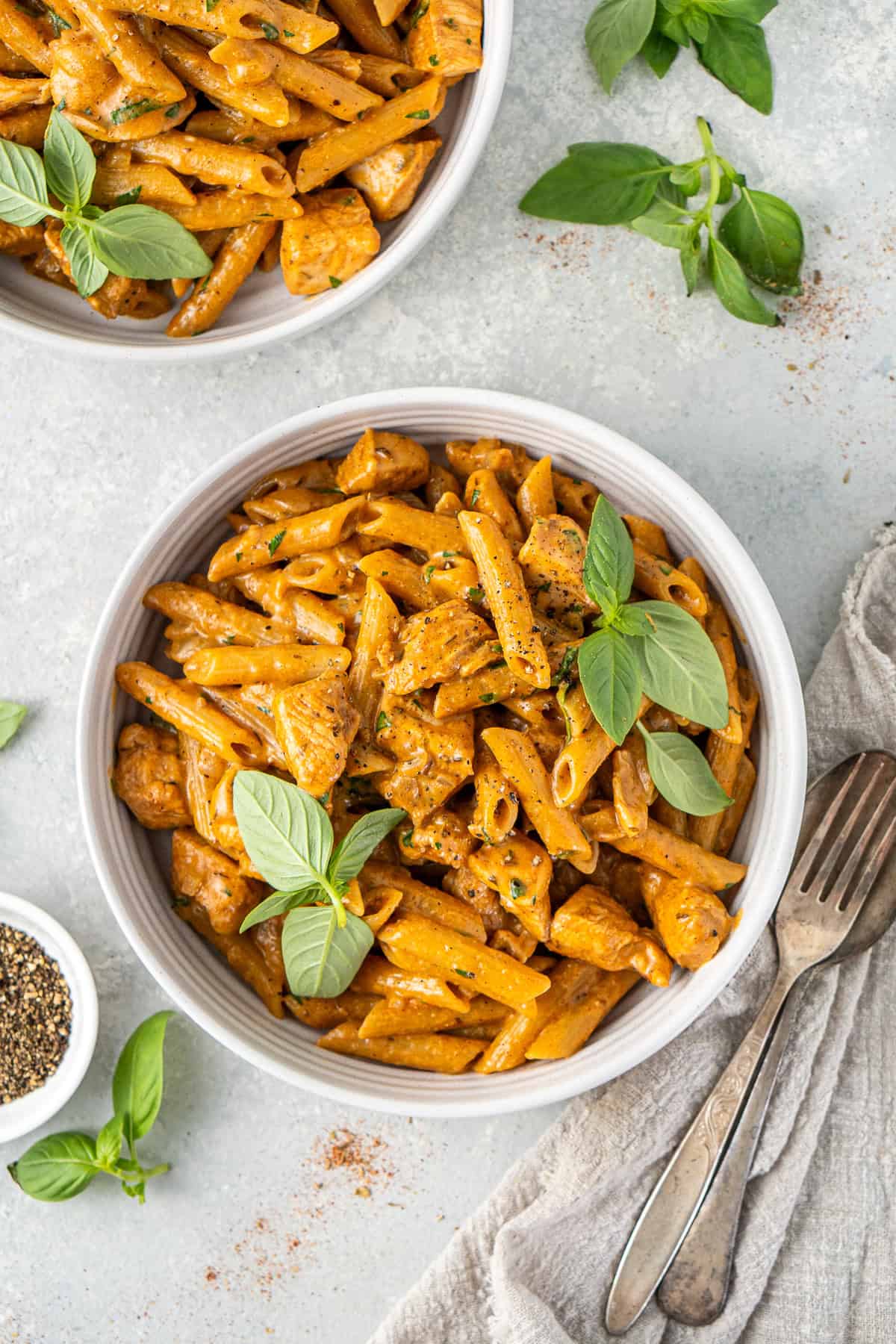 The creamy dairy free Cajun chicken pasta served into bowls with fresh basil.