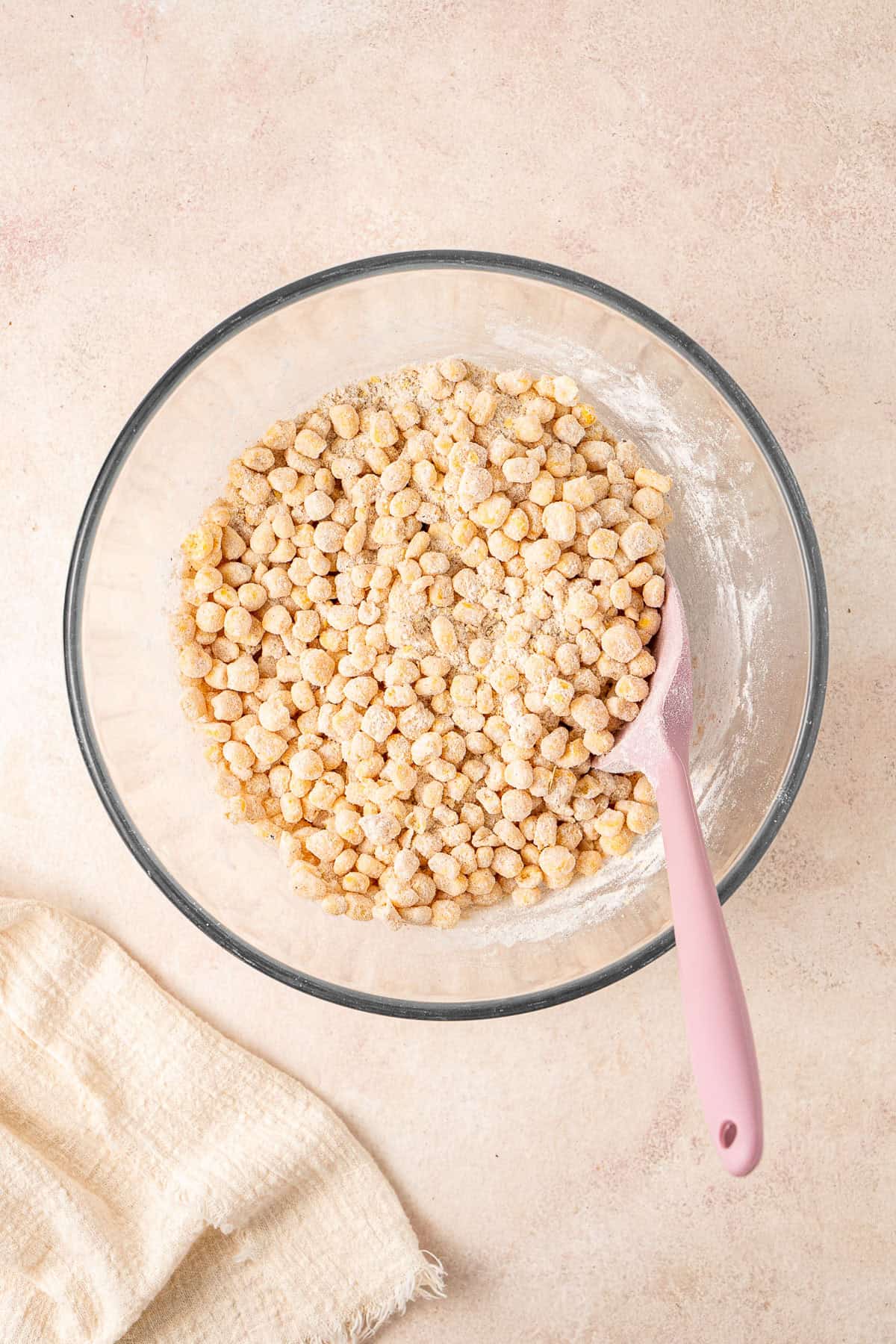 Mixing the corn with the dry ingredients in a bowl.