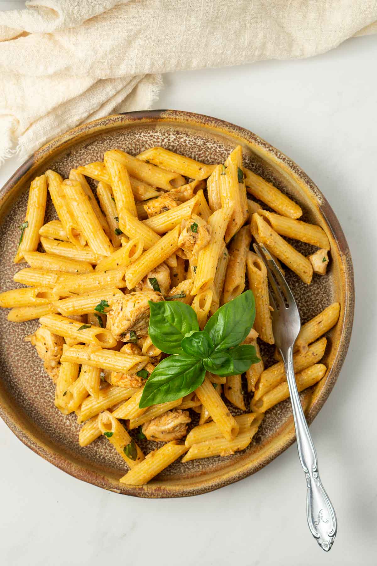 One pot creamy cajun pasta served up on a plate with fresh basil and a fork. 