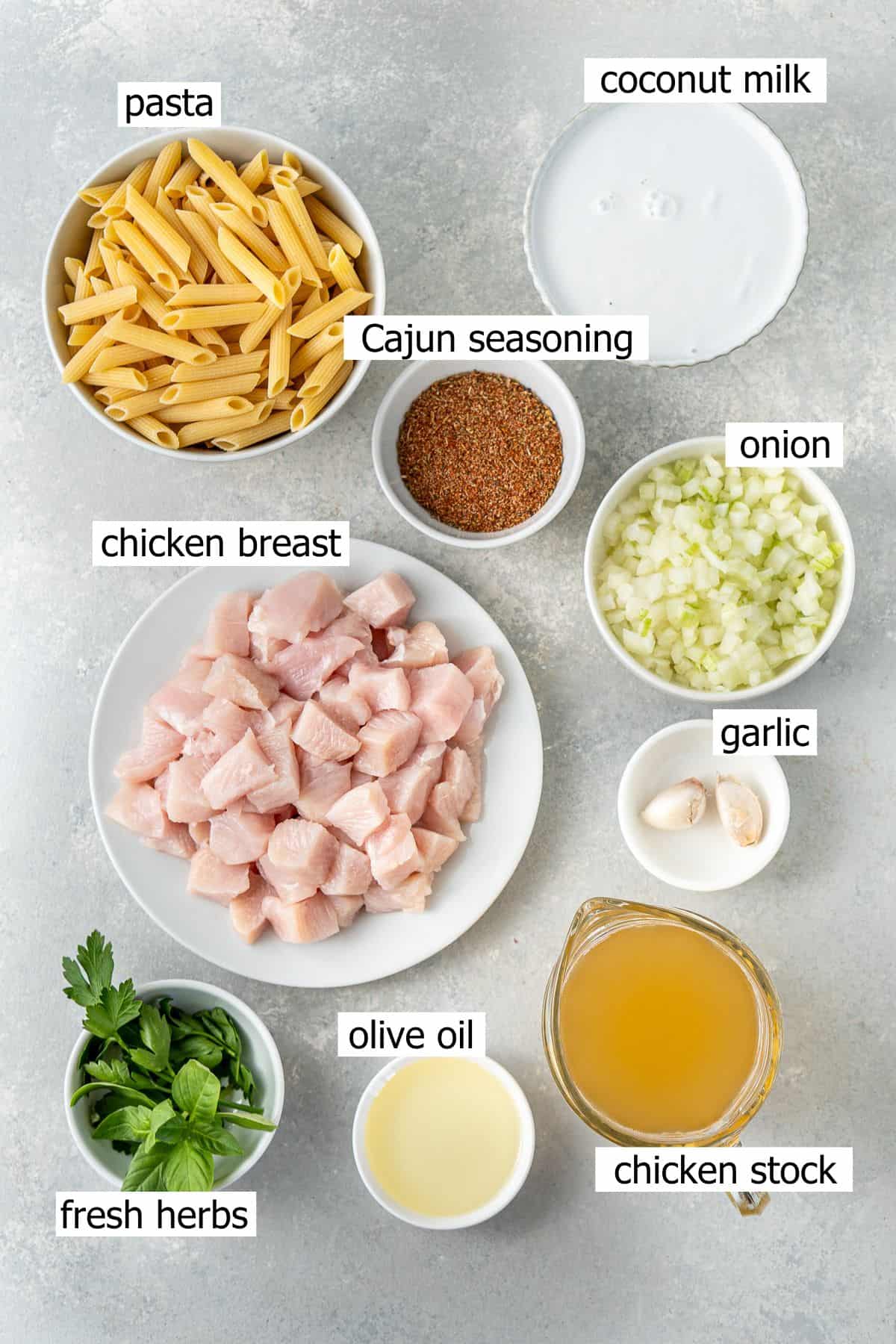 All ingredients needed to make dairy free cajun chicken pasta laid out in bowls.