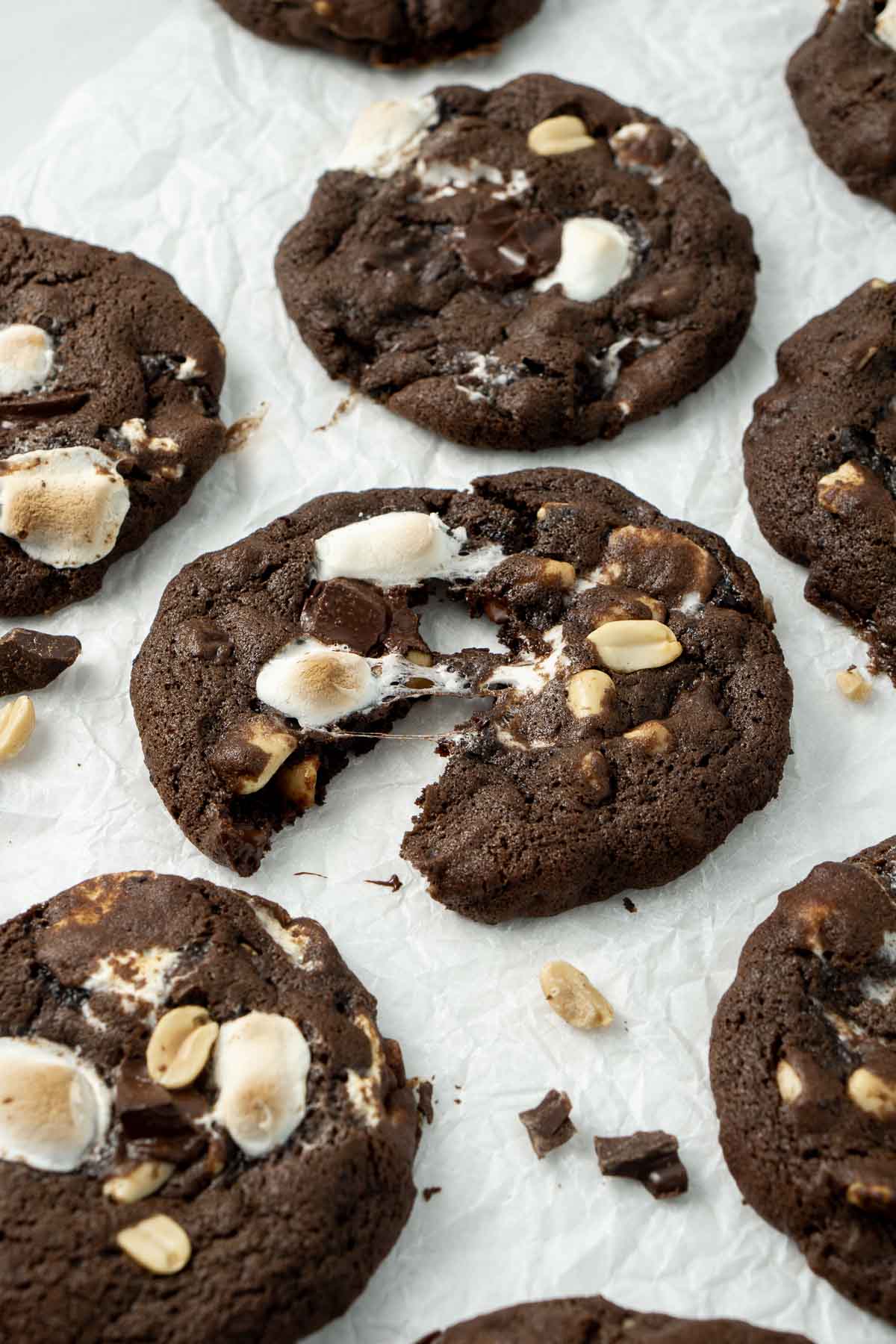 Rocky road cookies laid out on baking paper with gooey marshmallows and melted chocolate. 
