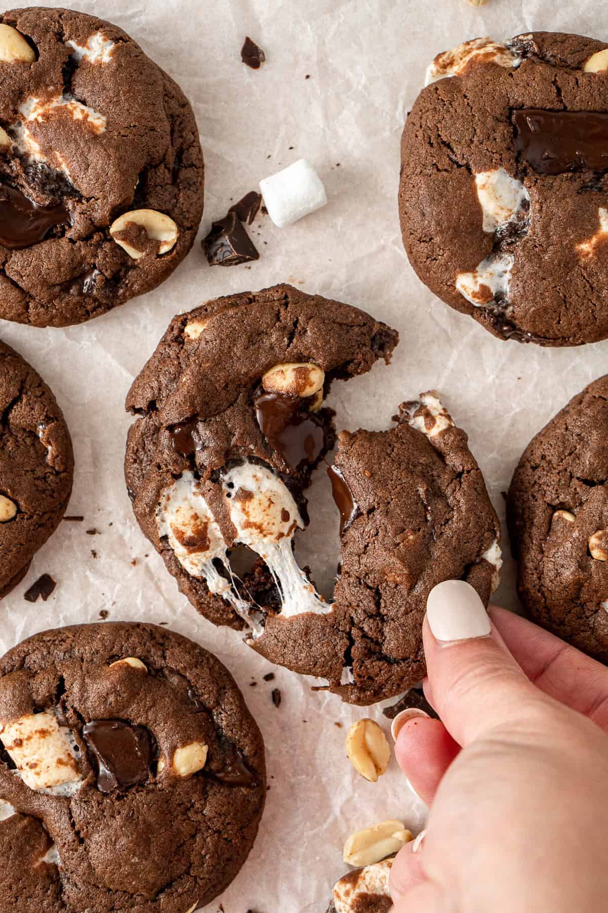 A hand breaking a rocky road cookie in half.