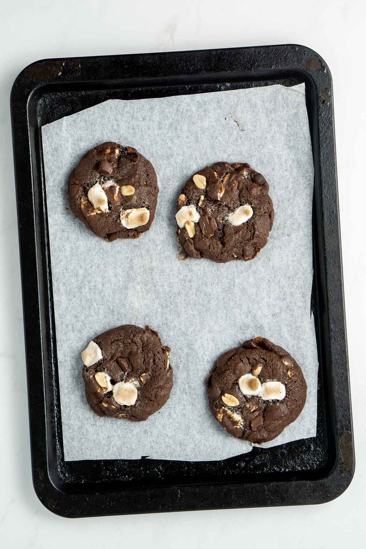 Freshly baked rocky road cookies on a baking tray.