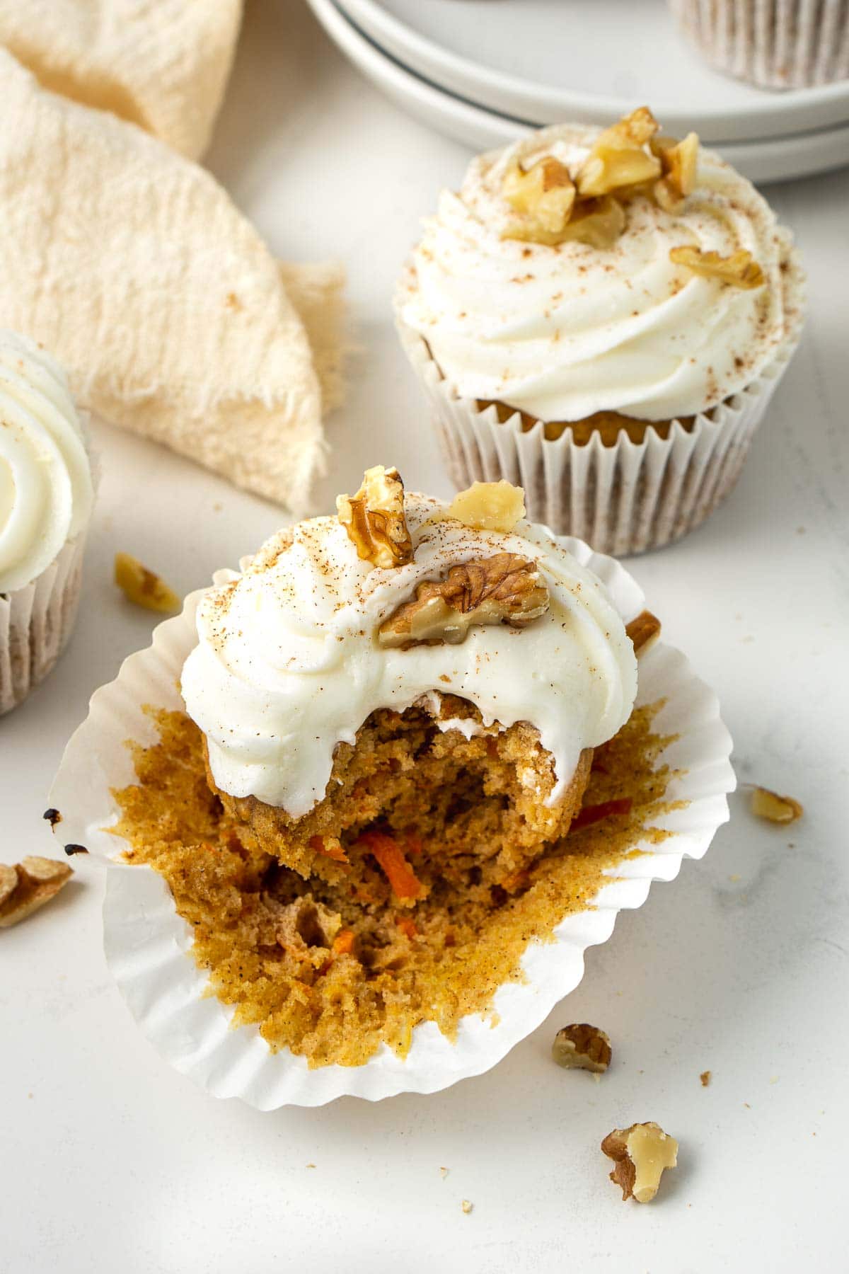 Close up of a carrot cake cupcake with a bite taken.