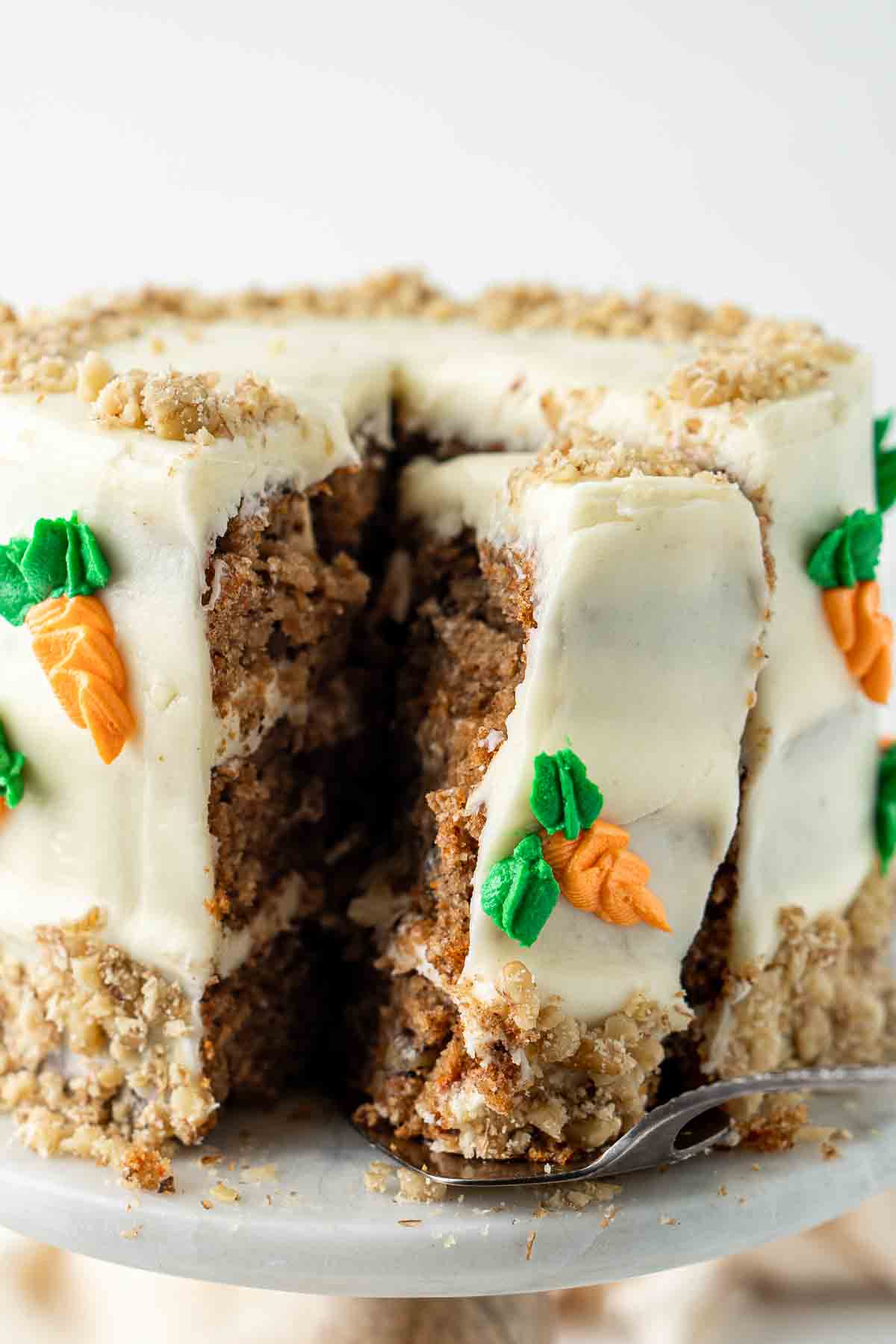A slice of carrot cake on a cake stand.