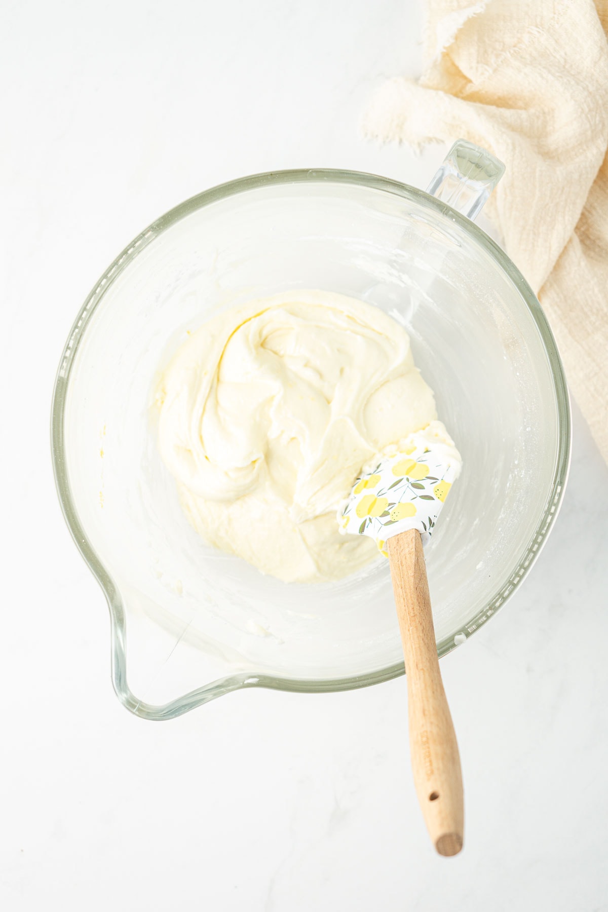 Creamy vegan lemon buttercream in a glass bowl with a spatula. 