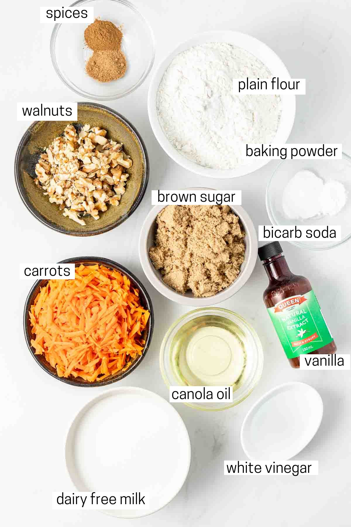 All ingredients needed to make vegan carrot cake cupcakes laid out in small bowls.