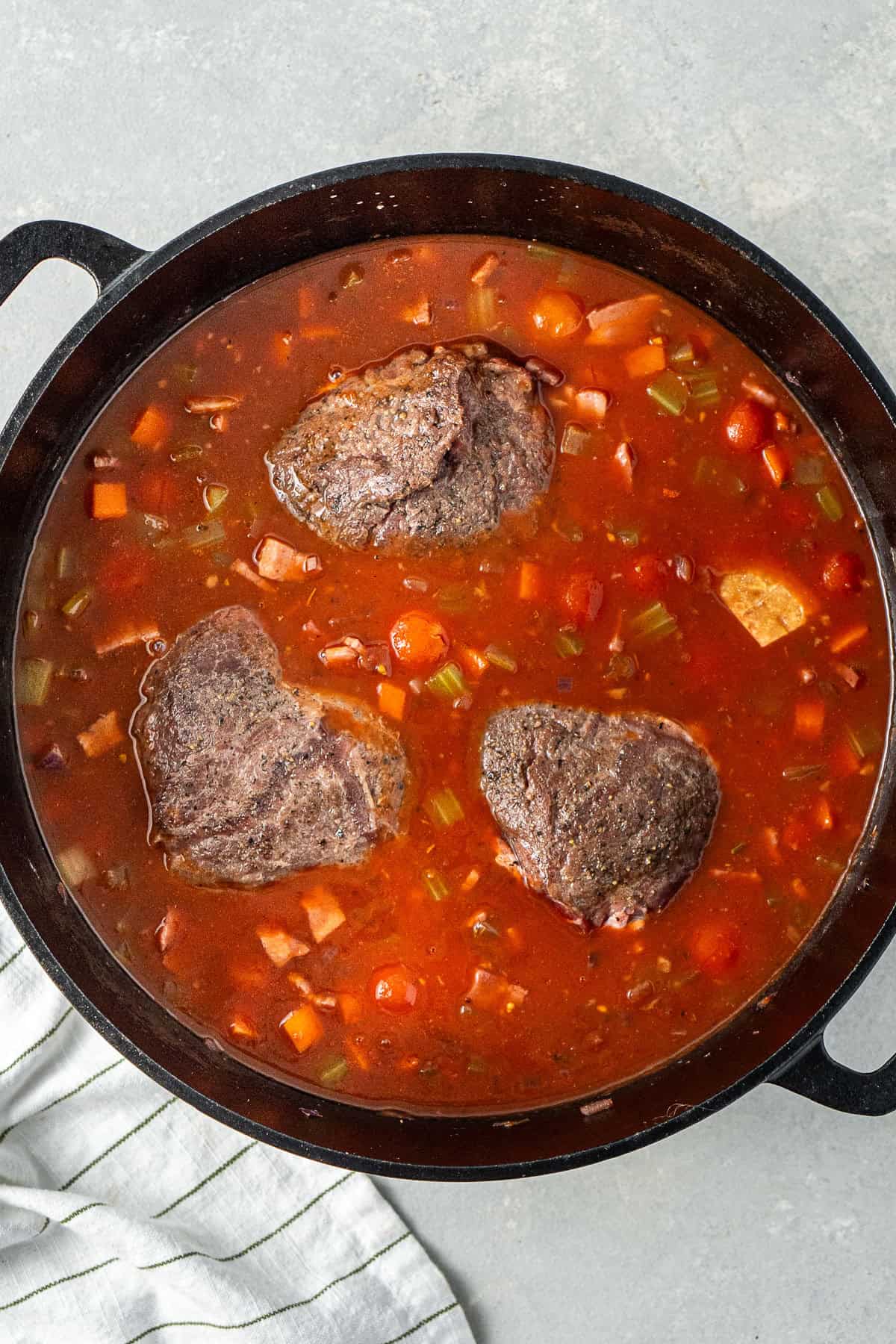 Adding the liquid and returning the beef cheeks to the pot.