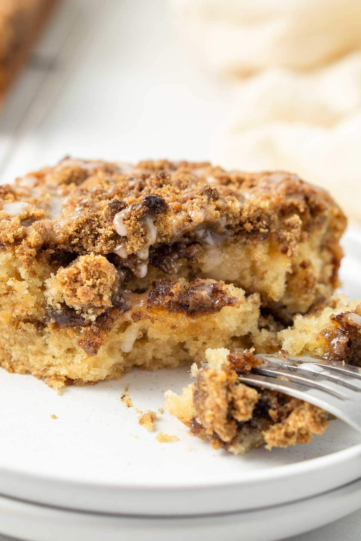 Close up of vegan coffee cake with glaze on a white plate. 