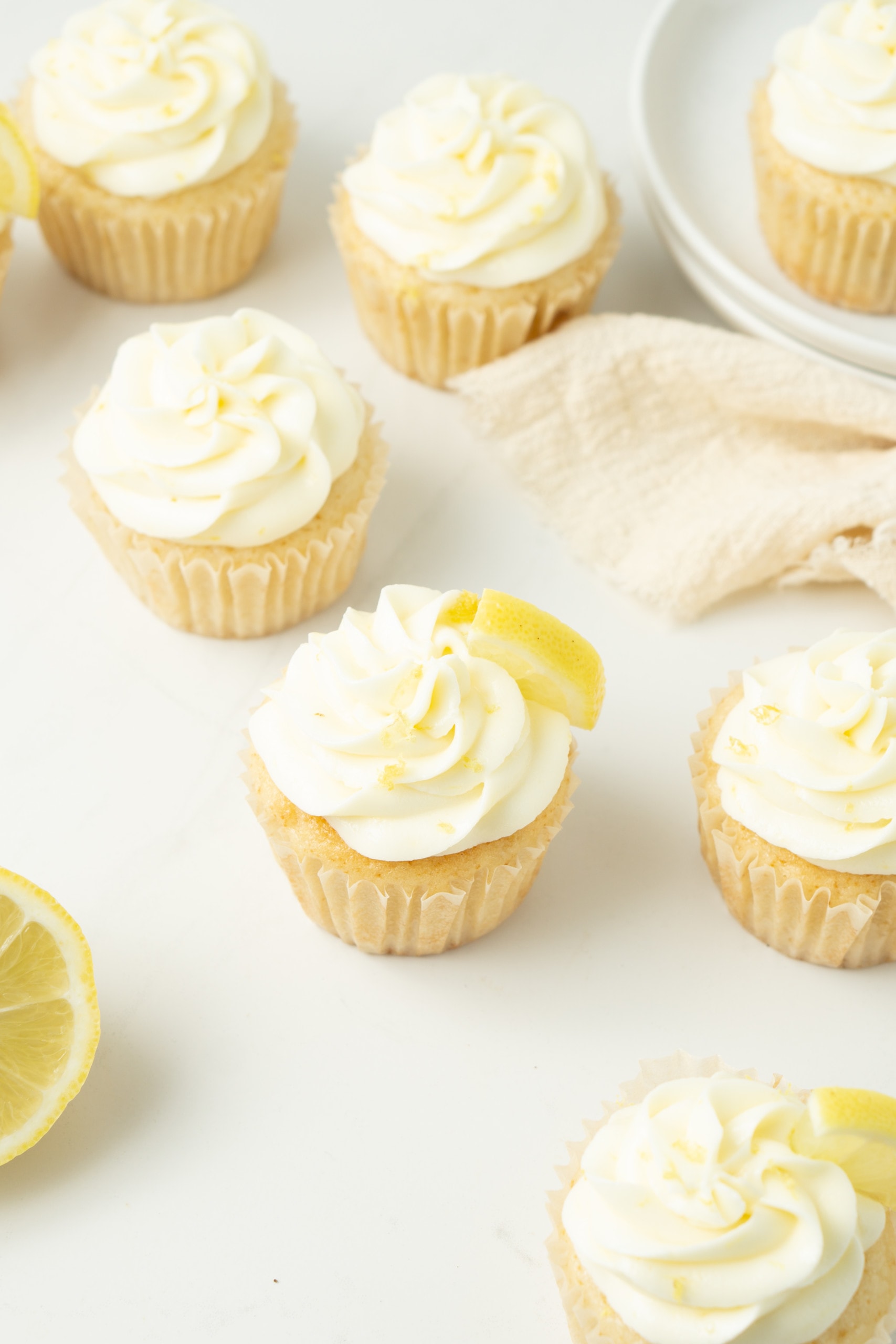 Vegan lemon cupcakes with lemon buttercream laid out on a table.