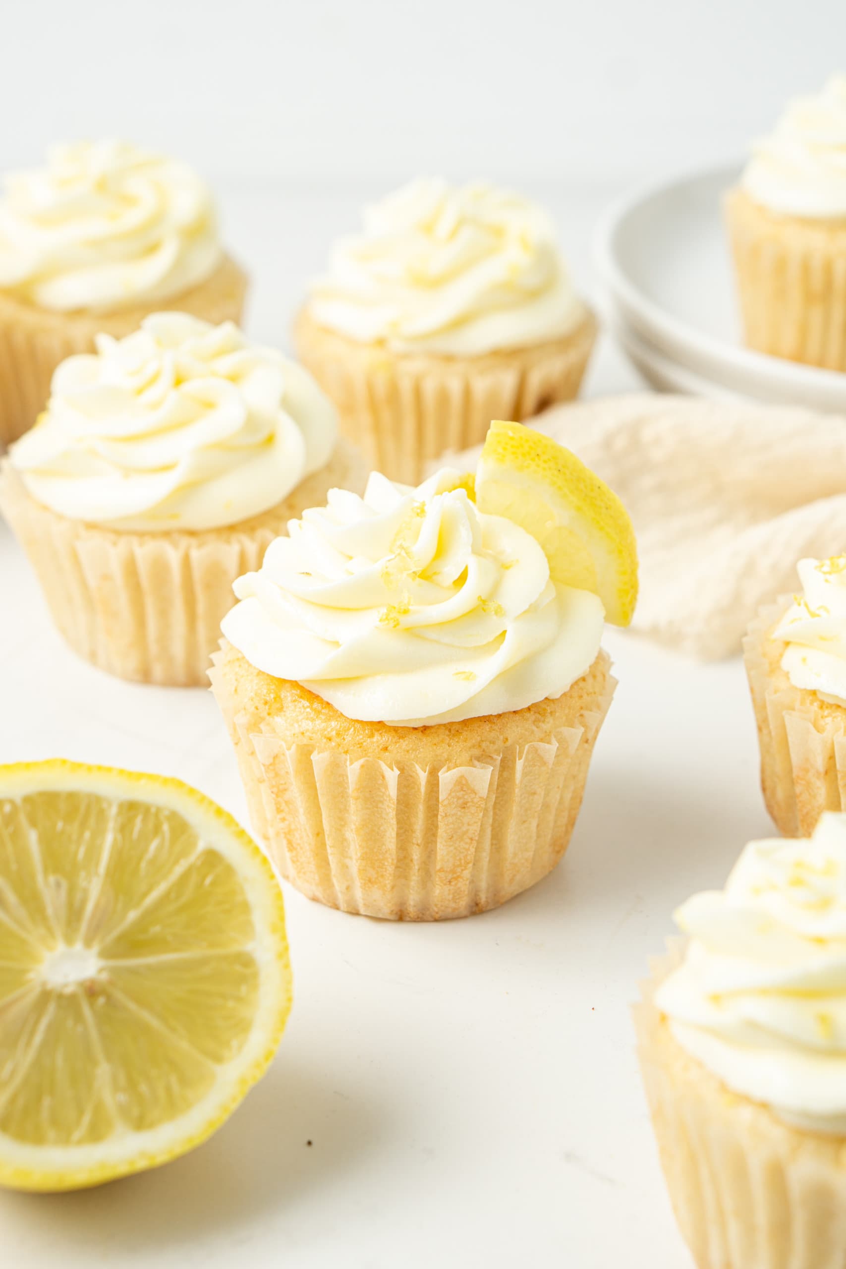 Close up of vegan lemon cupcakes with vegan lemon buttercream with a lemon wedge. 