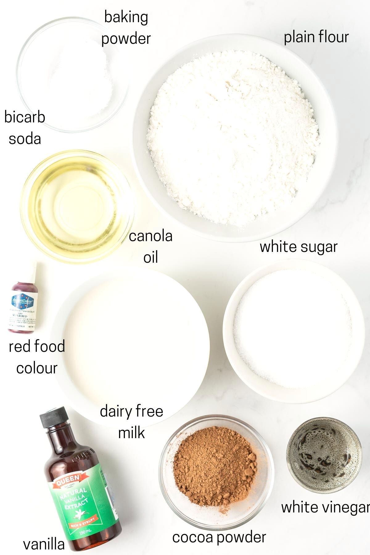 All ingredients needed to make red velvet cake laid out in small bowls.