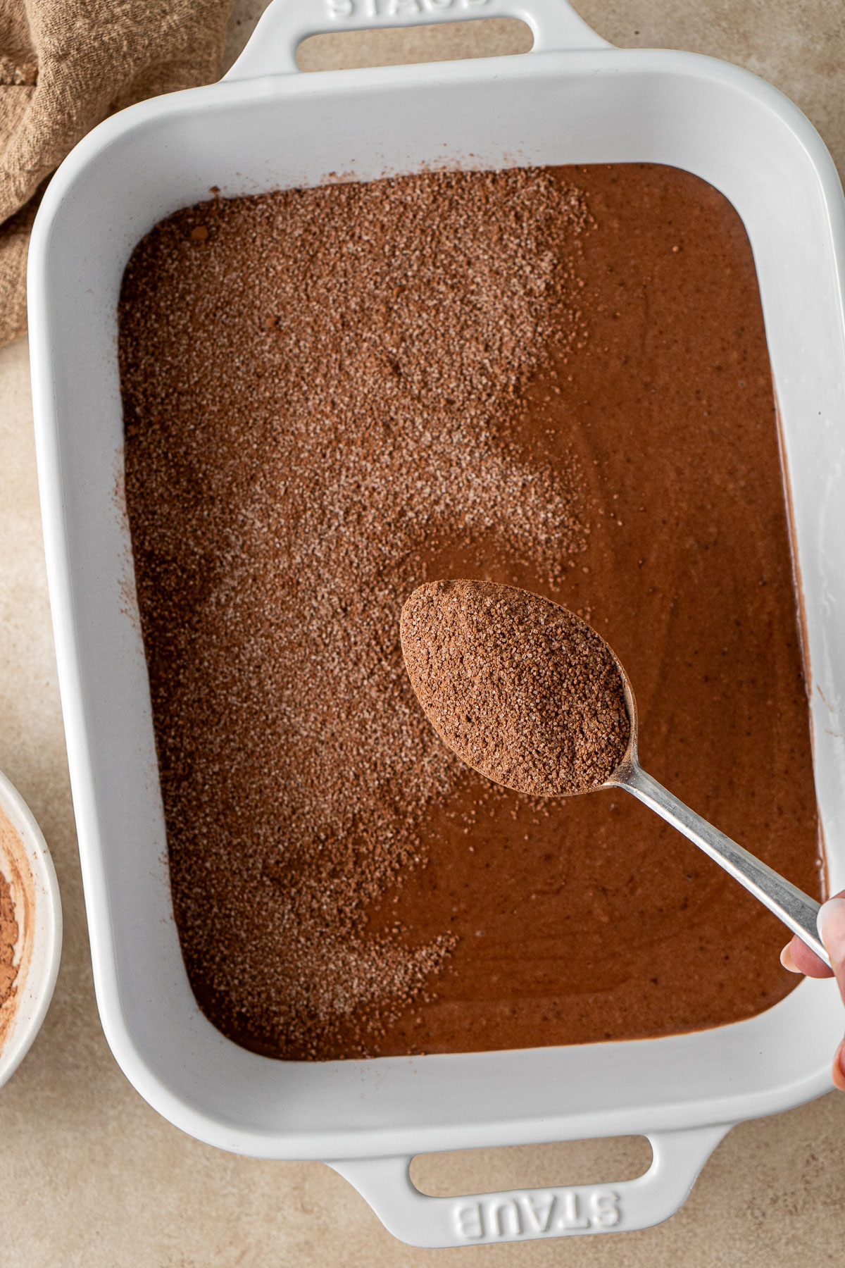 Sprinkling the topping over the pudding batter in the dish.
