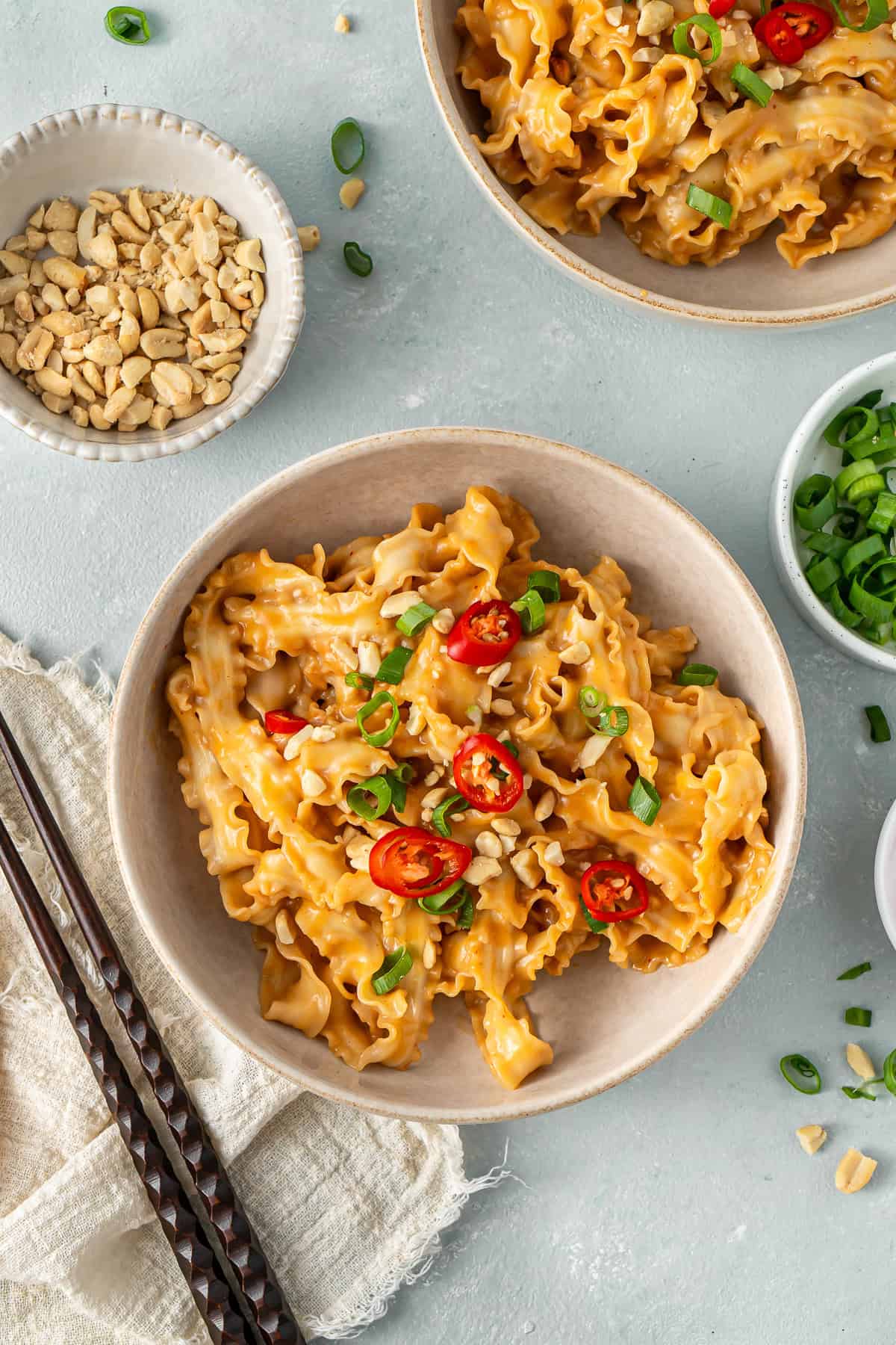 The spicy peanut butter noodles served into bowls topped with fresh chilli and spring onion.