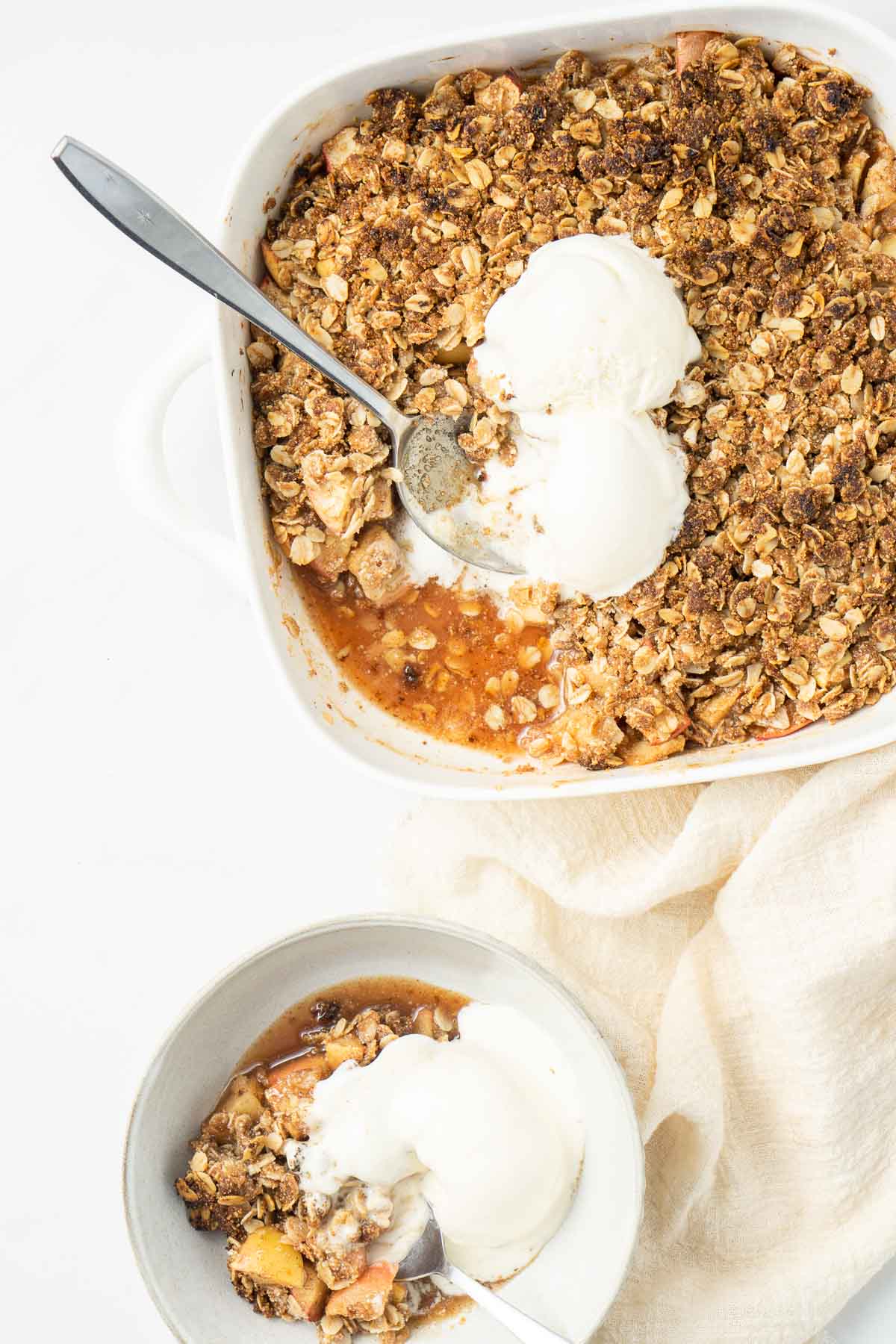 Vegan apple crumble with ice cream being served into a bowl. 