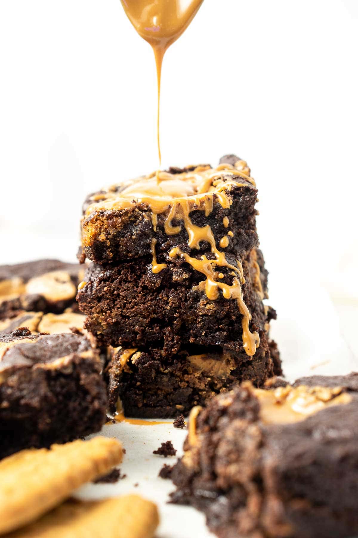 Vegan brownies stacked on top of each other drizzled with extra biscoff. 