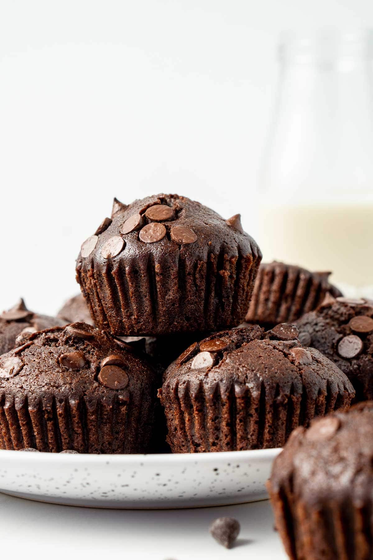 Vegan chocolate muffins staked on top of each other on a plate.