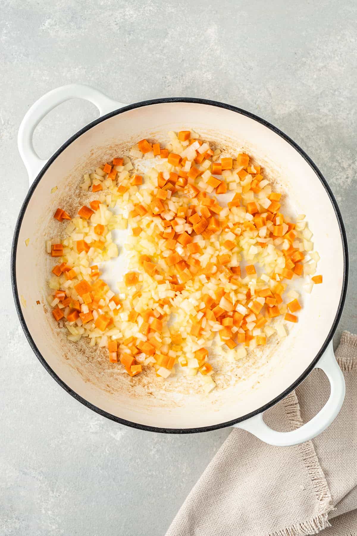 Sautéing the carrots and onions in a frying pan.