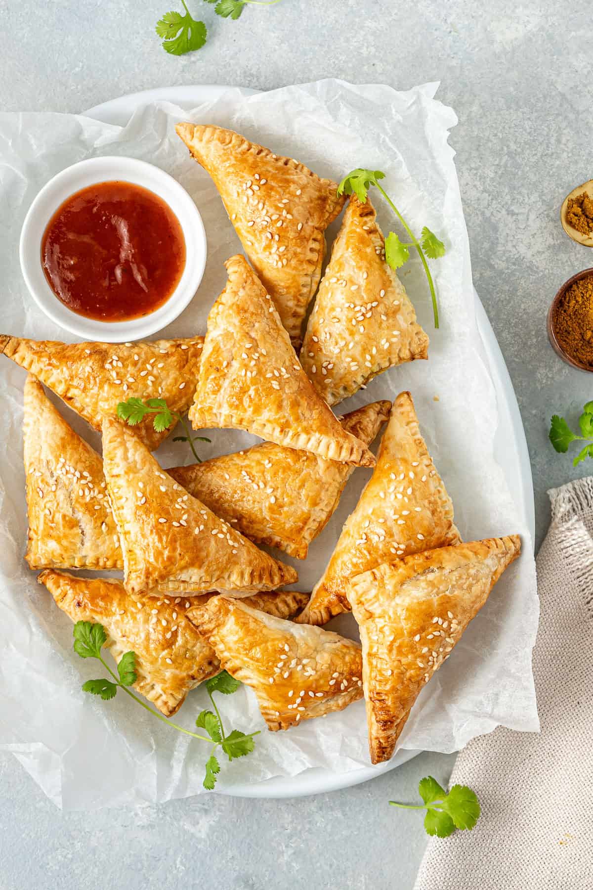 Vegetable curry puffs on a plate with tomato sauce.