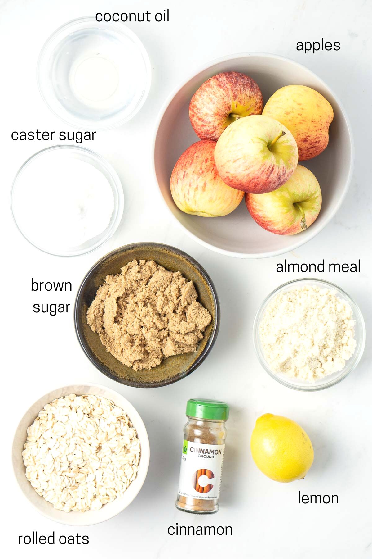 All ingredients needed to make vegan apple crumble laid out in small bowls.