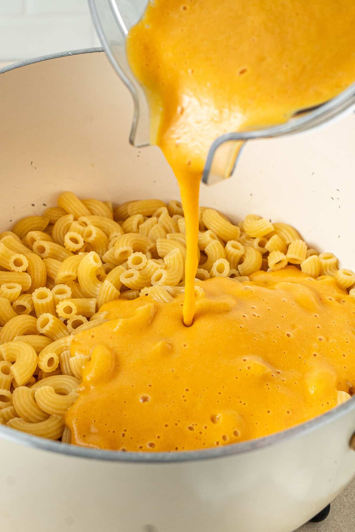 Pouring the sweet potato sauce over the pasta.