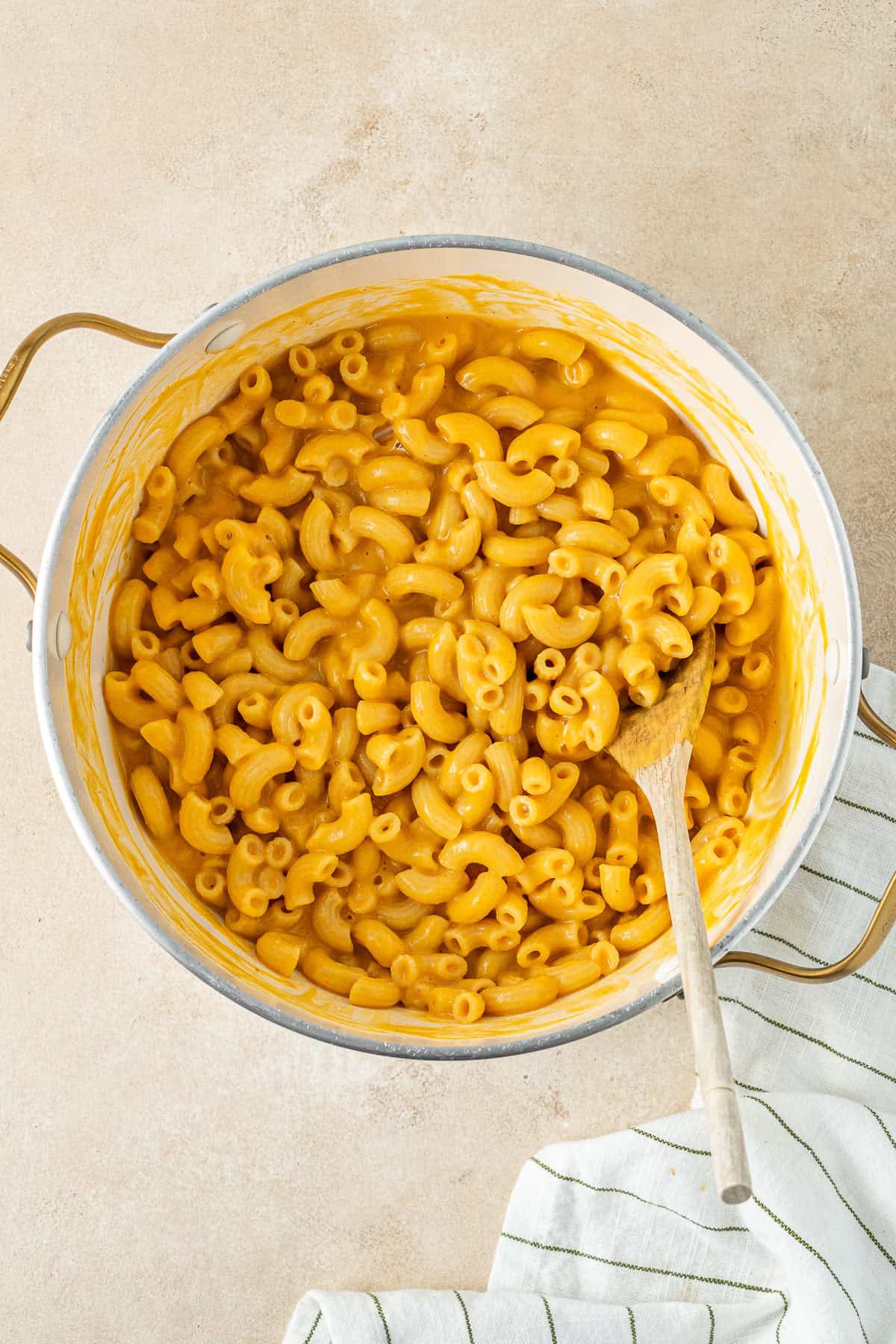 The sauce mixed through the cooked pasta in a pot with a wooden spoon.