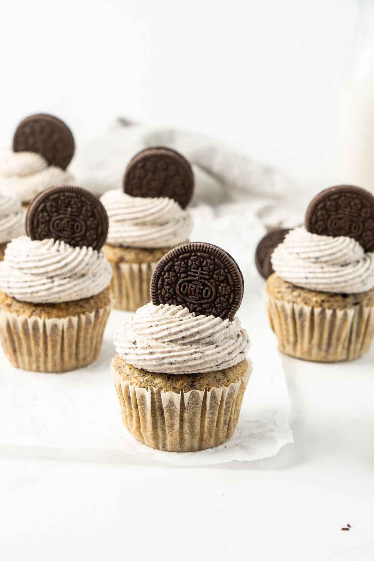 Vegan cookies and cream cupcakes with buttercream frosting and a Oreo sitting on top. 