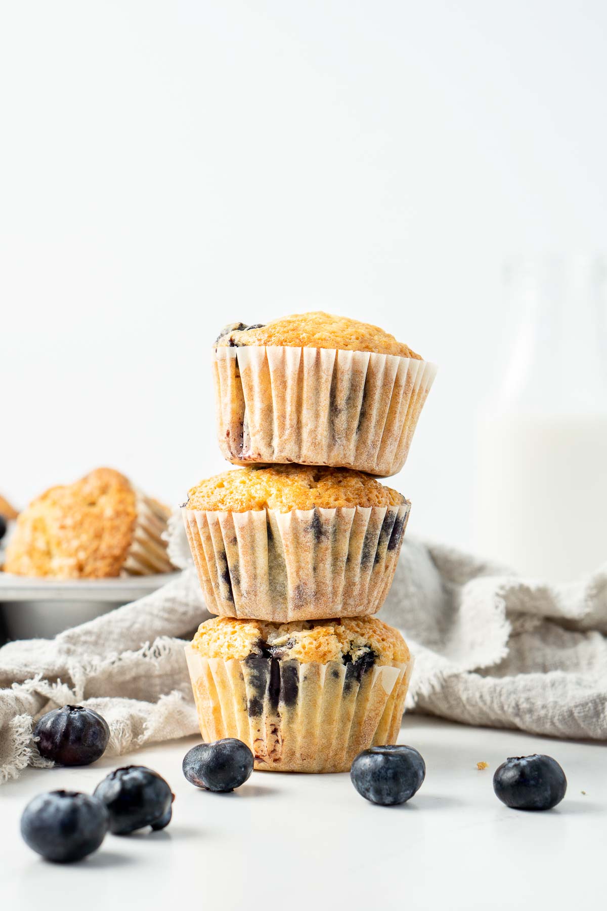 Three blueberry muffins stacked on top of each other.