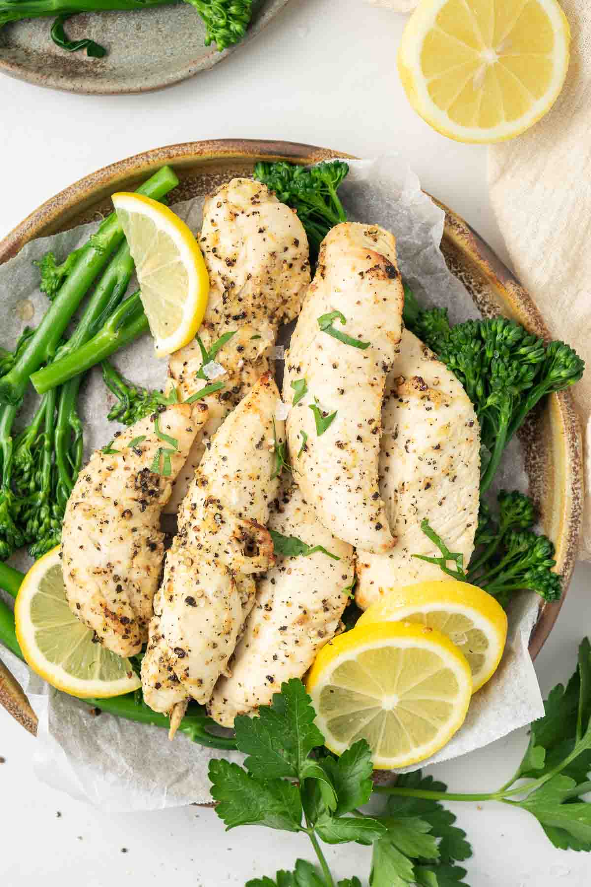 Chicken tenders with lemon and broccolini on a plate ready to serve.
