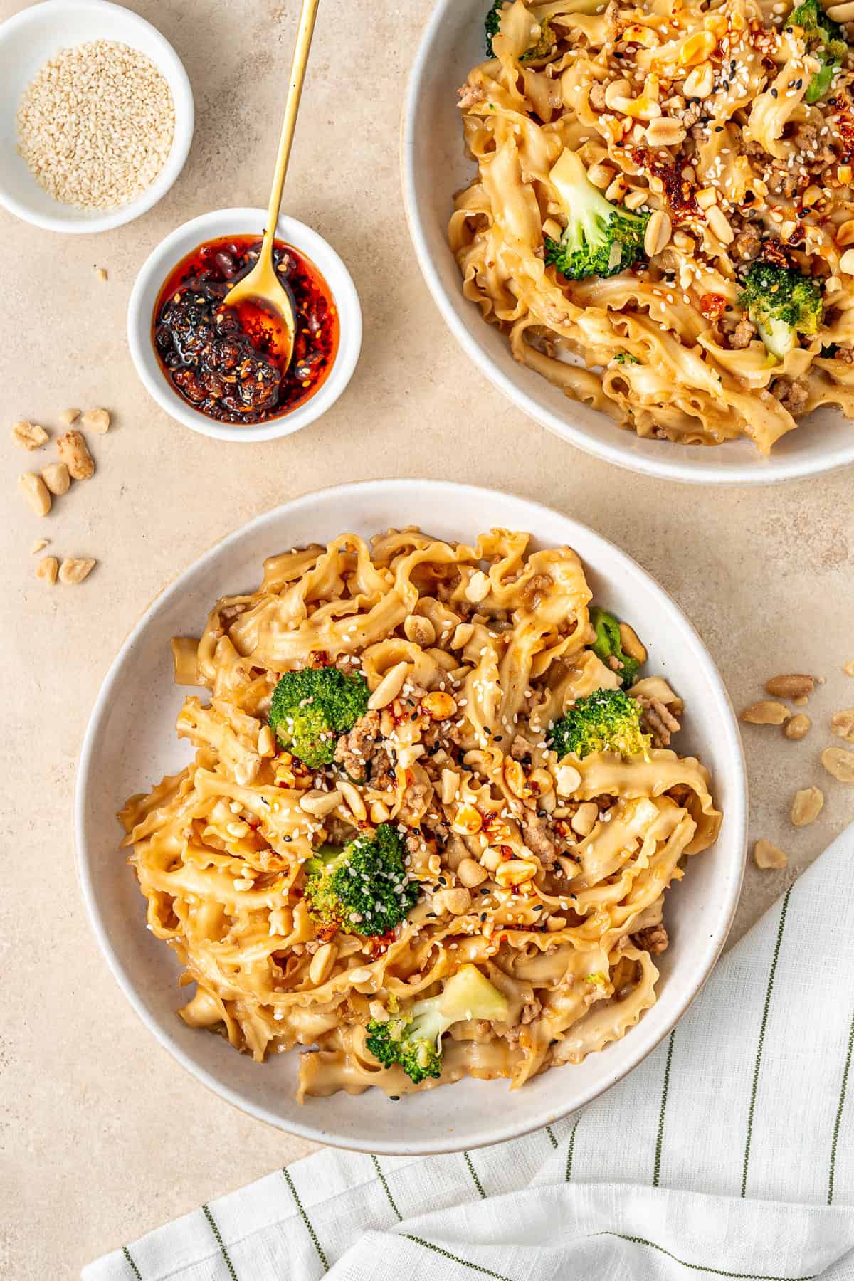 Spicy pork and peanut noodles served in a bowl with peanuts and sesame seeds. 