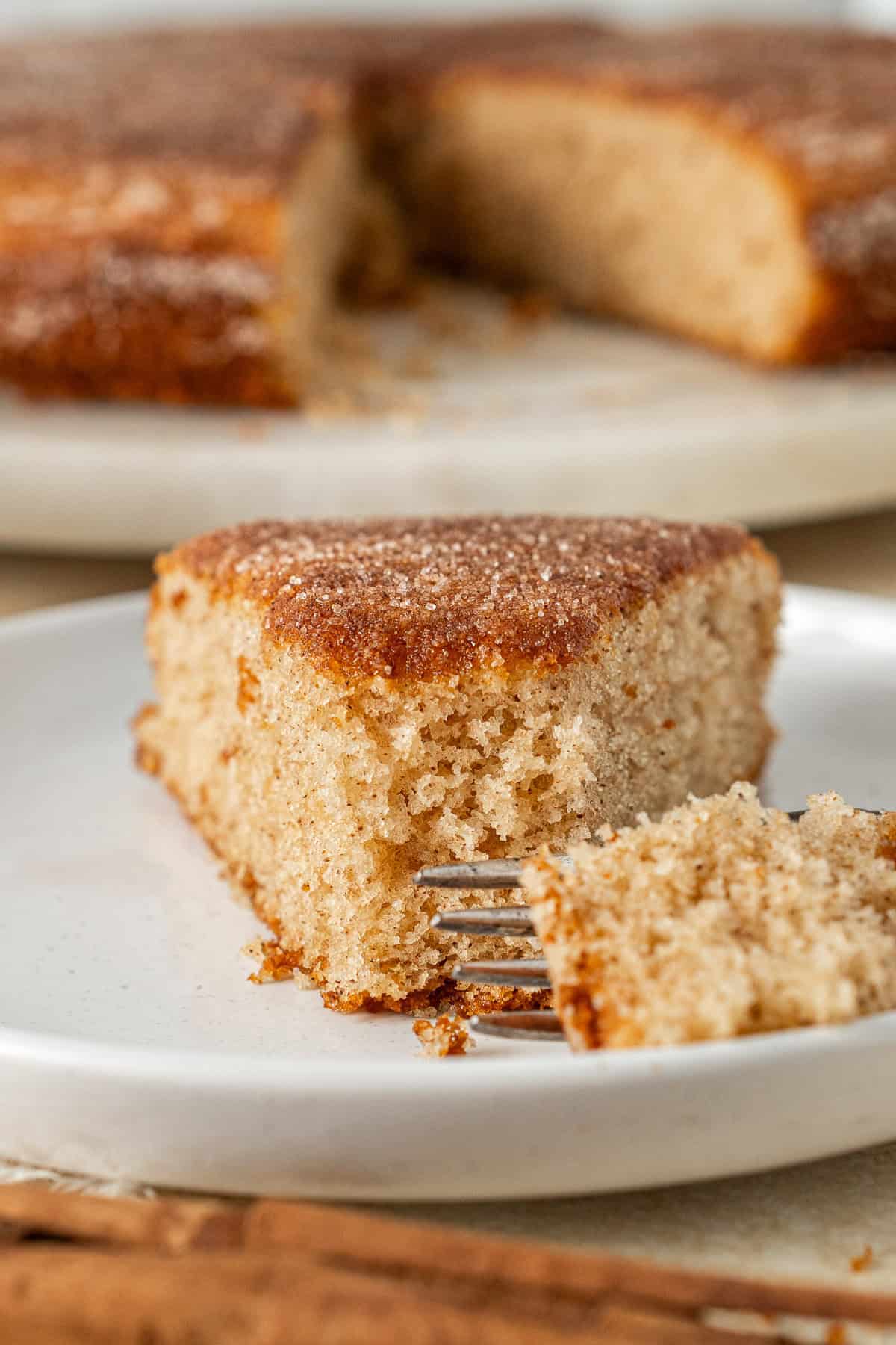 Close up of a slice of cinnamon tea cake on a white plate.