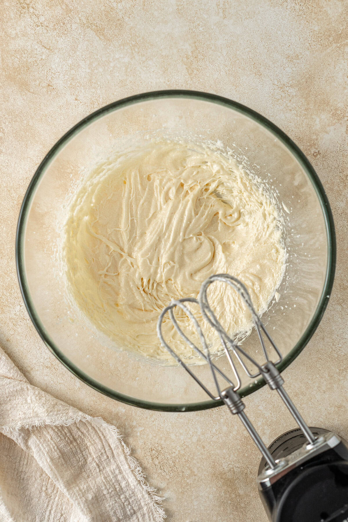 Bating together the butter and sugar with electric mixers in a glass bowl.