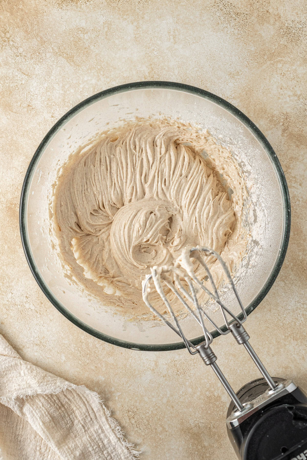 The creamy cake batter in a glass bowl with electric beaters. 