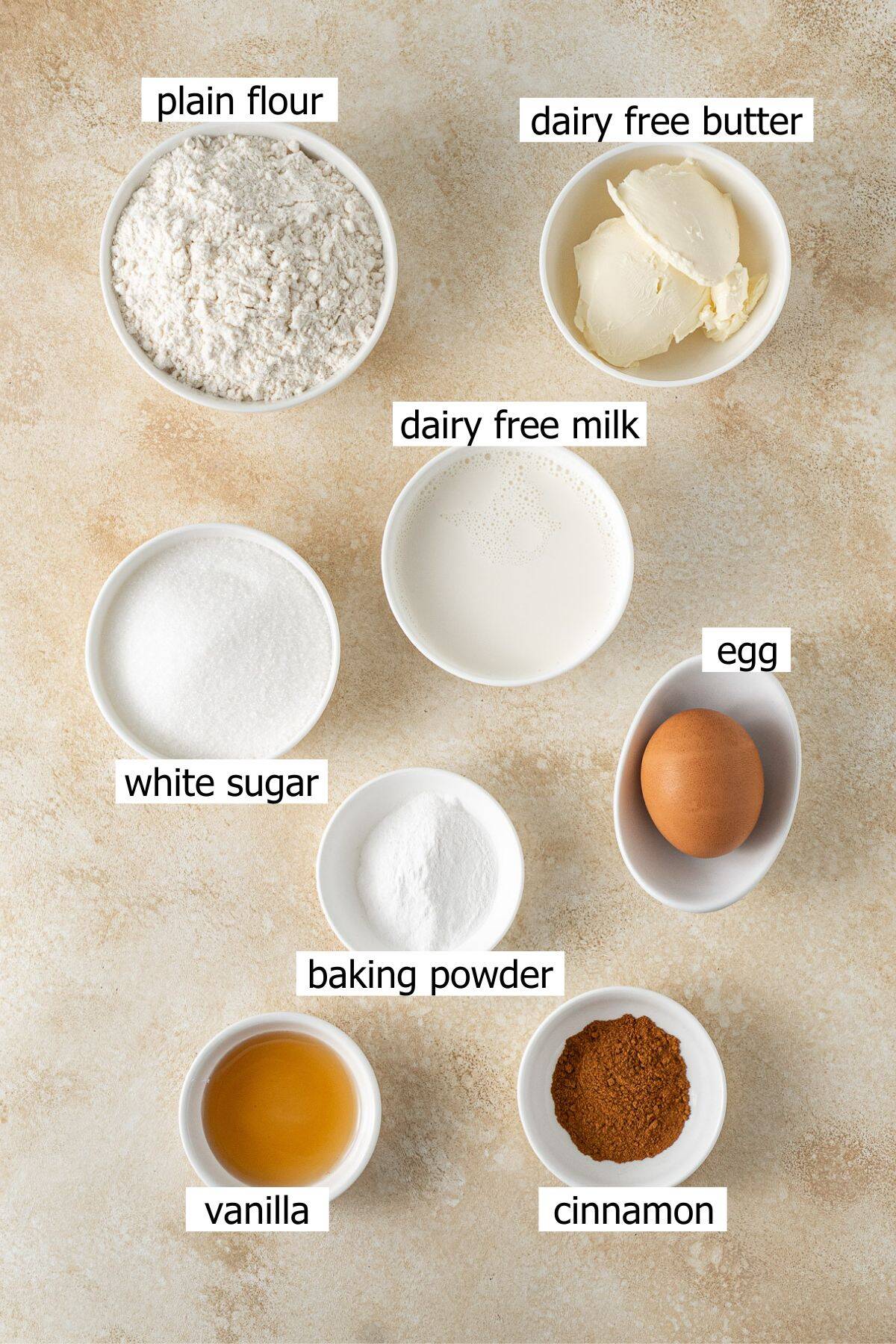 All ingredients needed to make cinnamon tea cake laid out in small bowls.