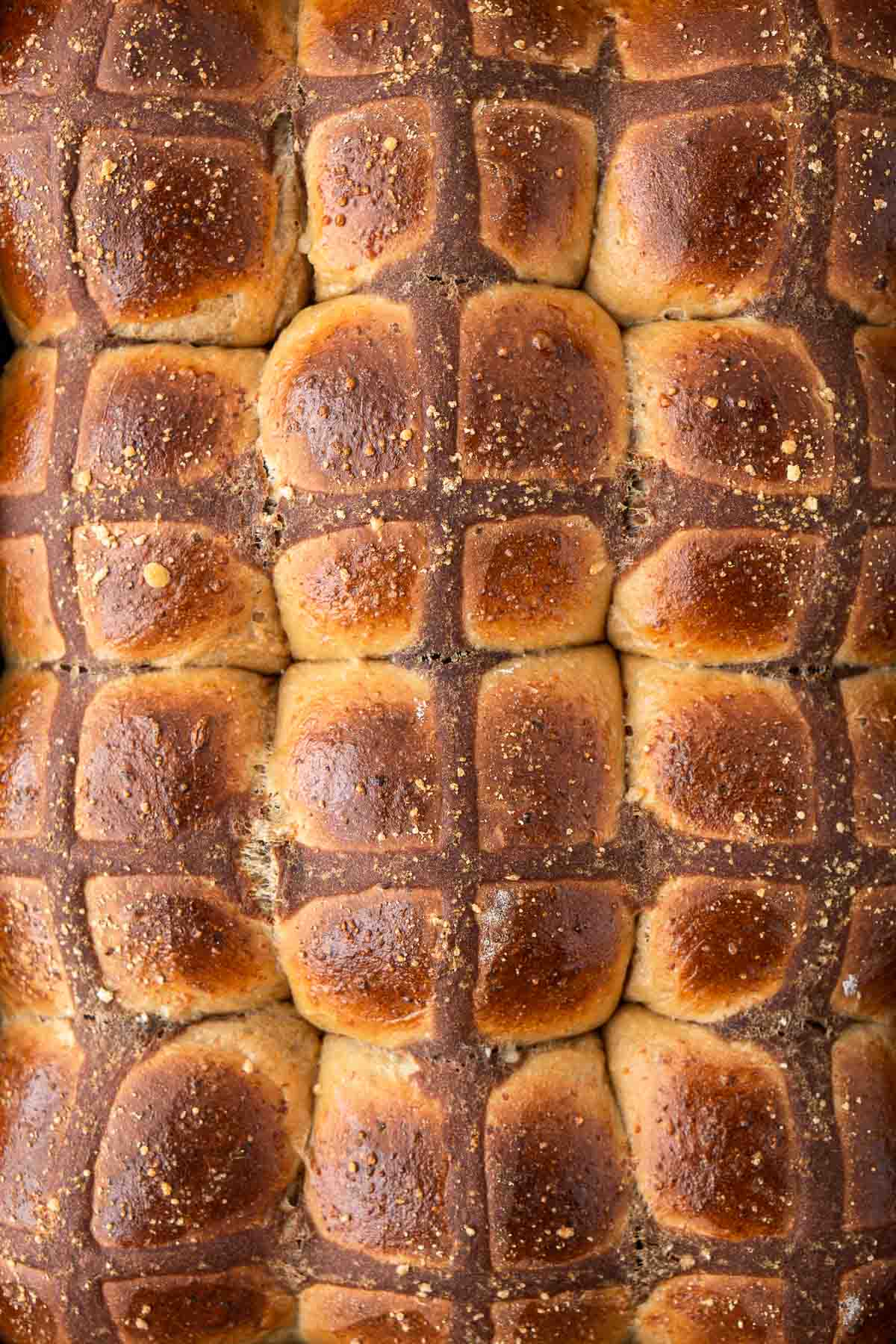 Close up of golden brown savoury hot cross buns.