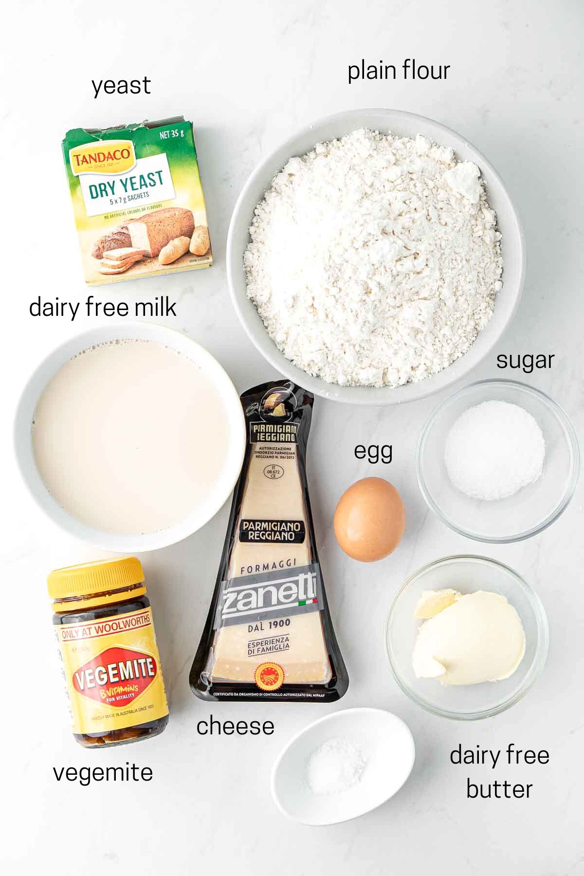 All ingredients needed for vegemite and cheese hot cross buns laid out in bowls.