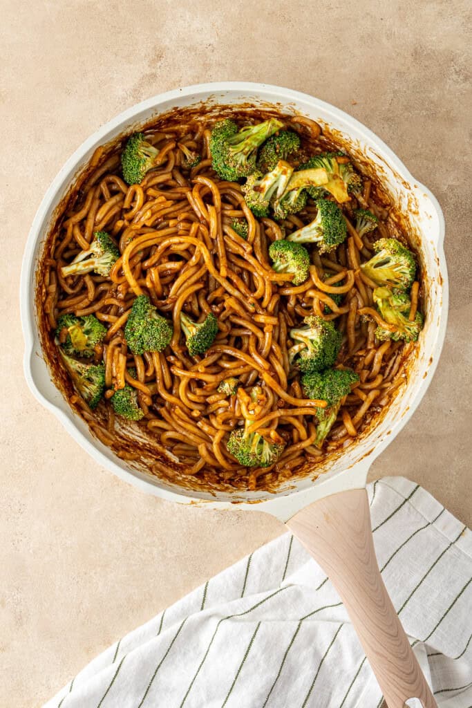 The noodles, sauce and broccoli in the frying pan.