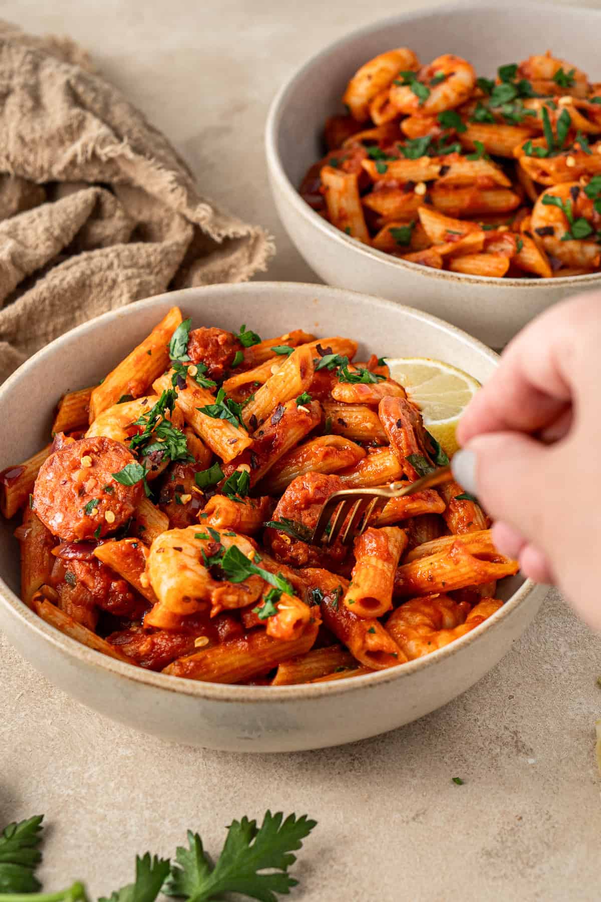 A hand taking a bite of the pasta with a fork.
