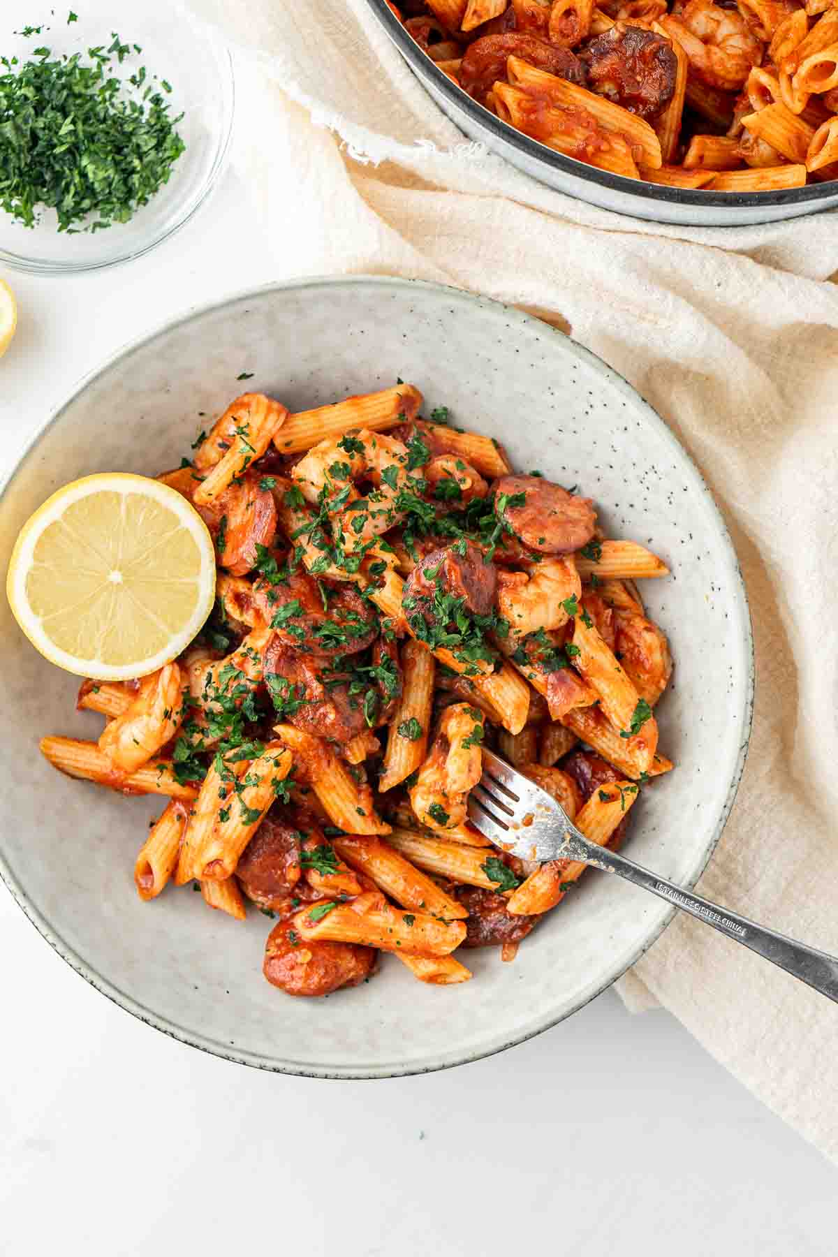 Prawn and chorizo pasta with parsley and lemon in a bowl with a fork.