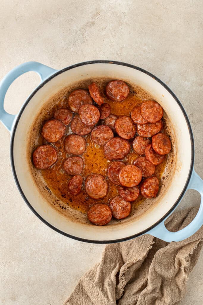Frying the sliced chorizo in a large pot.